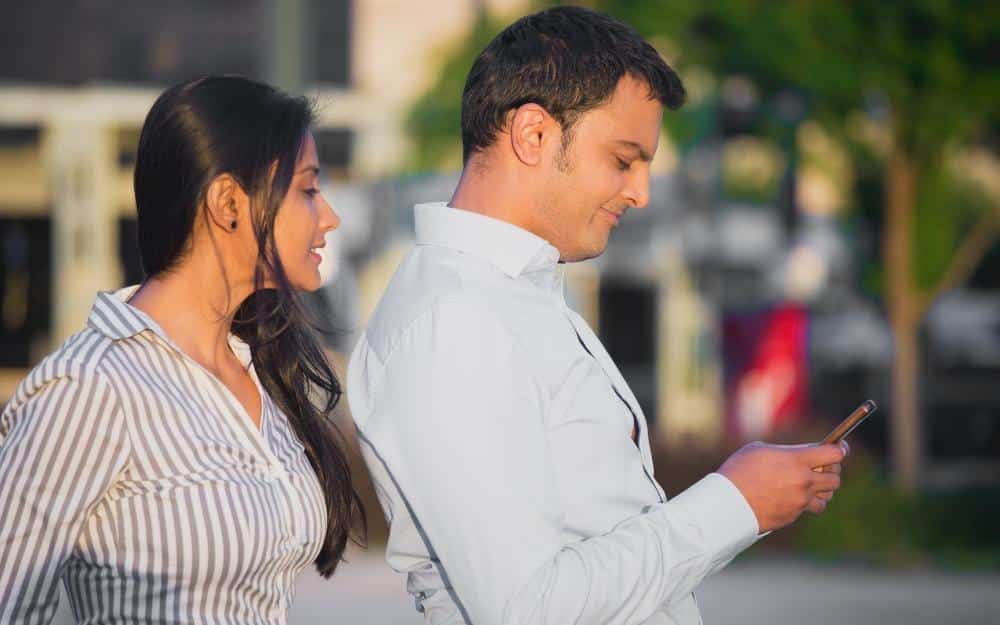 picture of a man sending inappropriate texts with his woman looking over his shoulder
